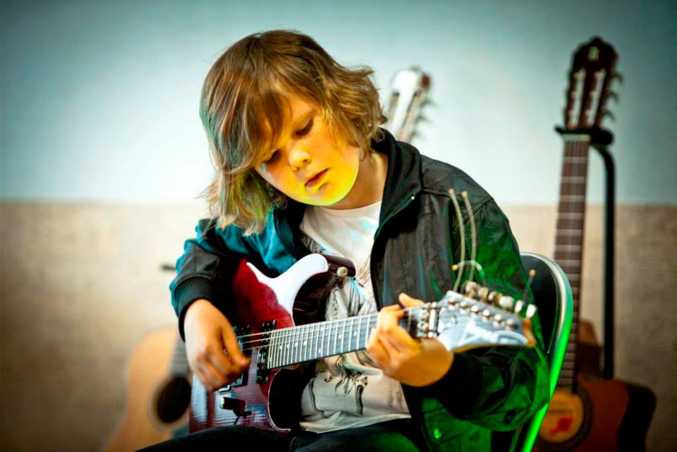 chłopiec uczy się grać na gitarze